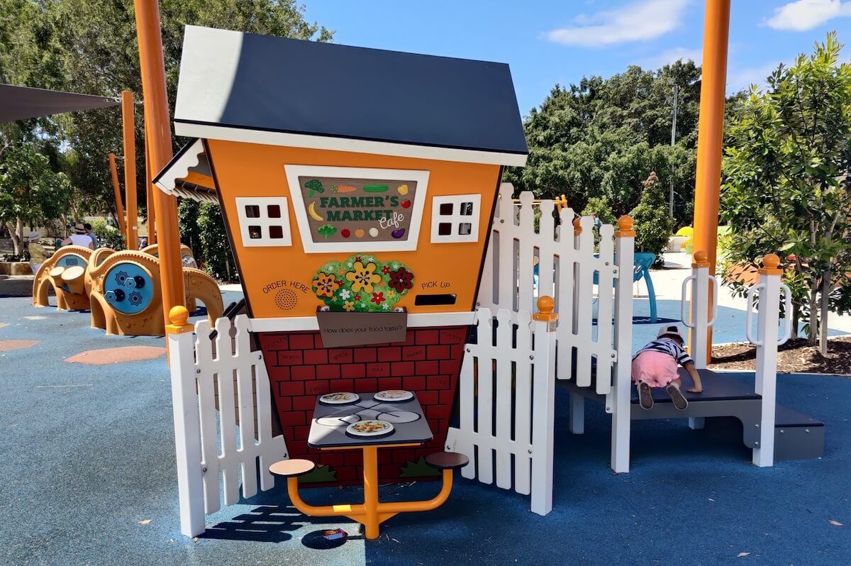 Fun farmer&rsquo;s market cubby house with sensory play elements at the Hills District All Abilities Playground in Brisbane.